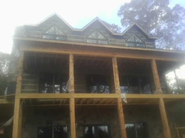 Dormers and porch framing on a large log home under construction — Roof Coating work by our crew in Marlboro